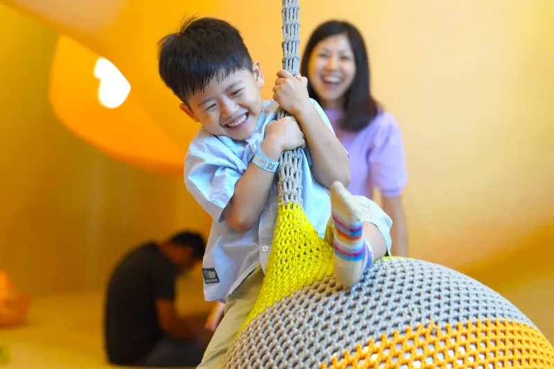 A party guest swinging on the woven ball swing at UFOREA Penang