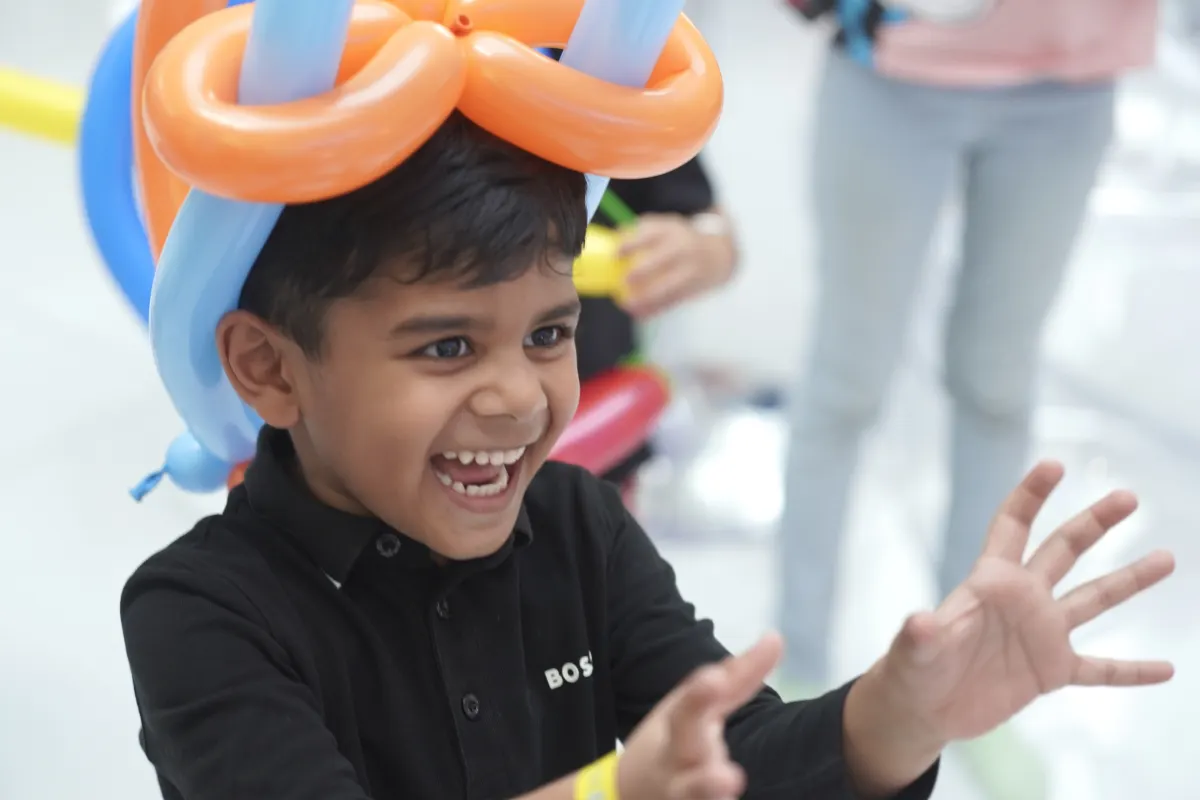 A young guest laughing in a balloon hat at a UFOREA Penang birthday party