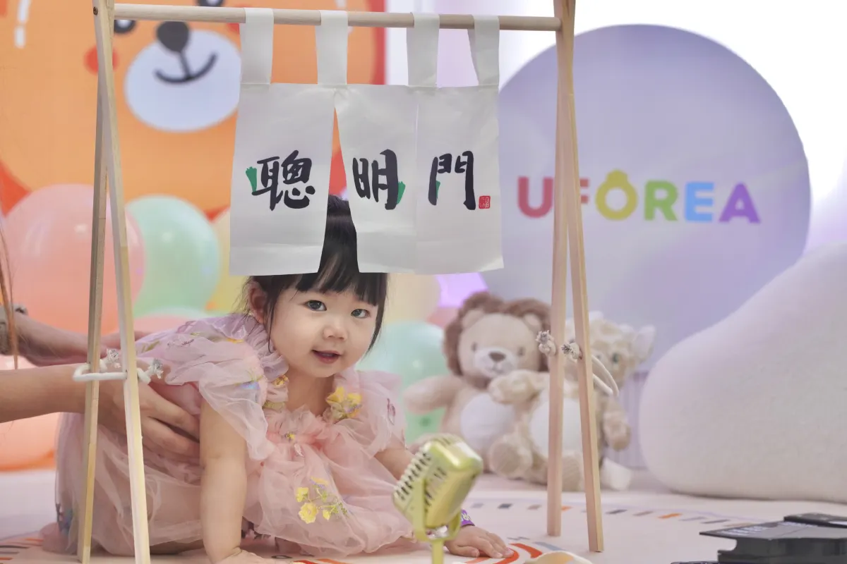 A toddler crawling through the clever gate during a first birthday tradition at UFOREA Penang