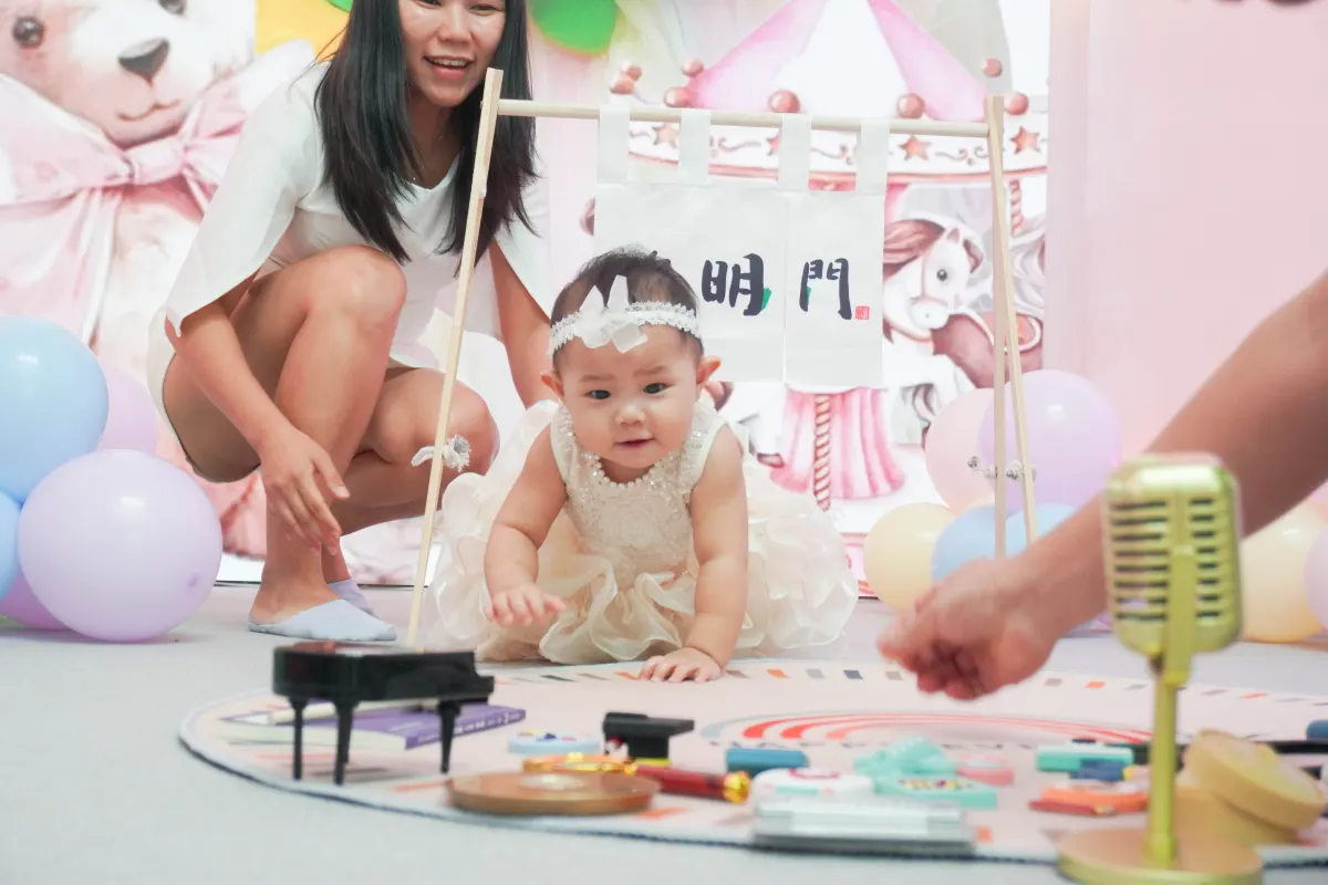 A baby crawling toward the draw-lots picks at a first-birthday ceremony at UFOREA Penang
