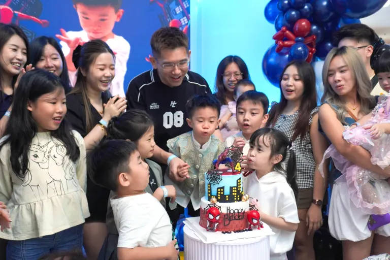 The cake moment at a hosted superhero-themed birthday party at UFOREA Penang, with young guests gathered to blow out the candles