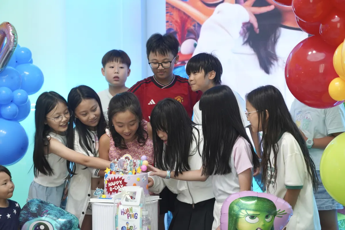 Older kids crowding around the birthday cake at a UFOREA Penang party
