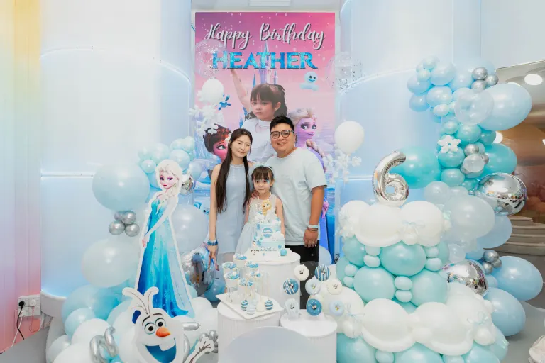 A winter-princess themed birthday setup at UFOREA Penang with blue and white balloon garlands, a personalised backdrop and a dessert table
