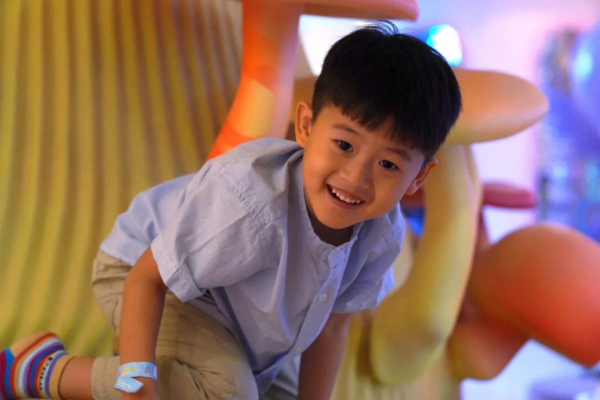 A grinning boy clambering through the play sculptures at UFOREA Penang