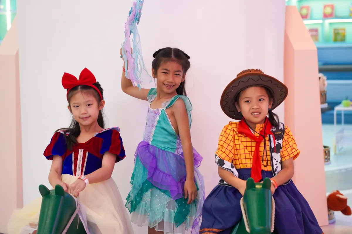 Three girls in fairytale and cowgirl costumes riding rocking horses at UFOREA Penang