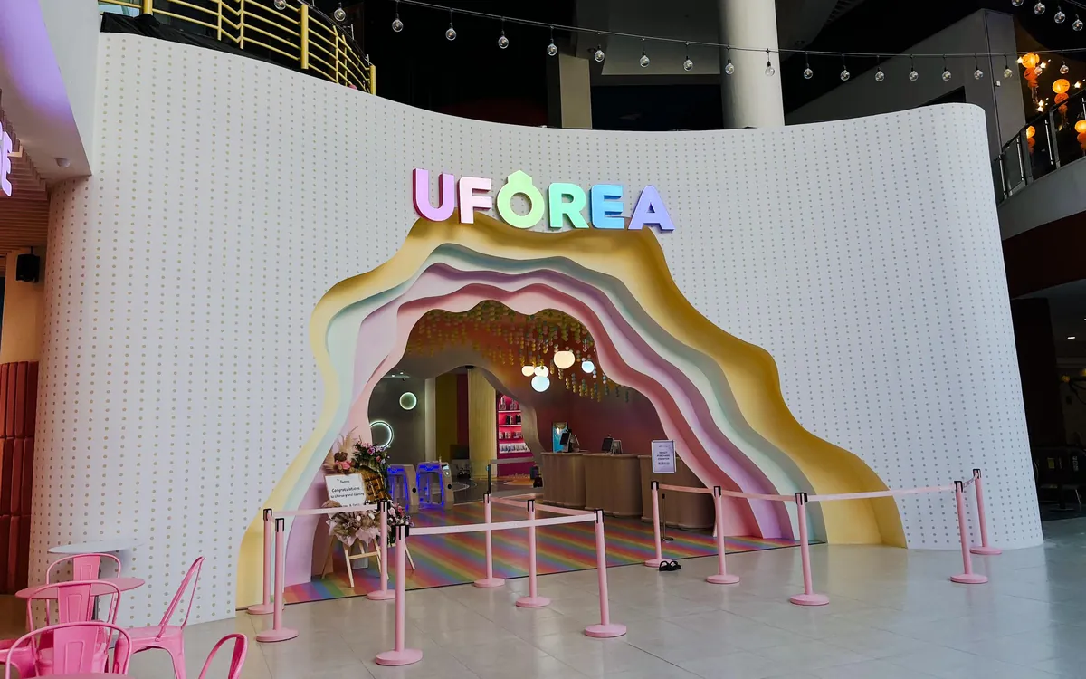 The pastel rainbow entrance arch and glowing ticket counter inside UFOREA Penang
