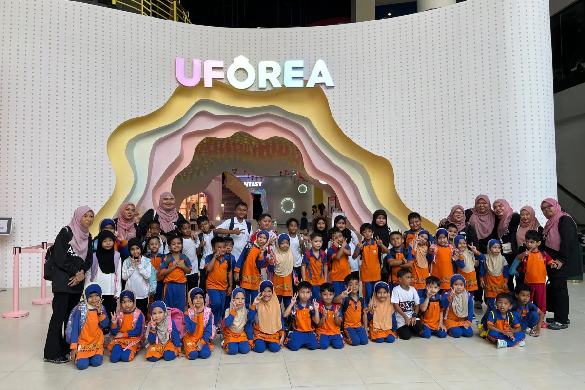 A kindergarten group with their teachers at the UFOREA Penang entrance arch
