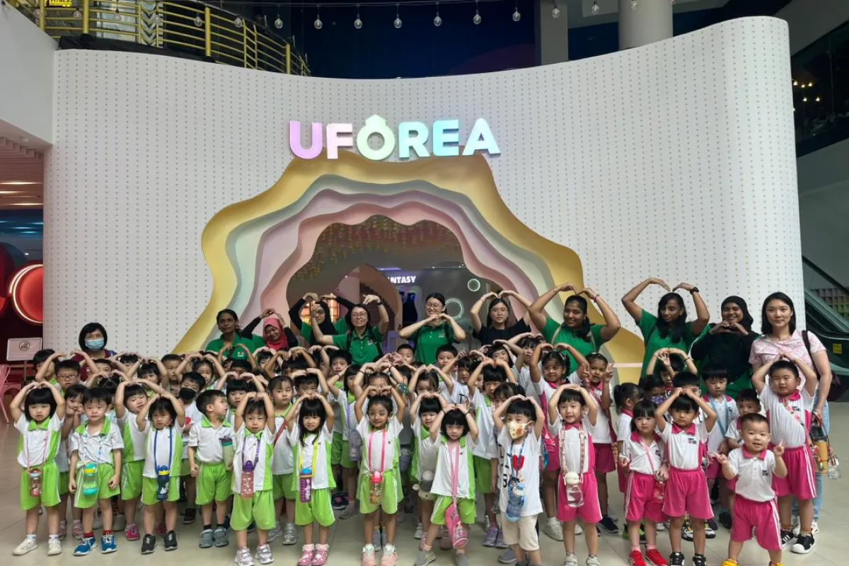 Kindergarten children making heart signs at the UFOREA Penang rainbow arc entrance