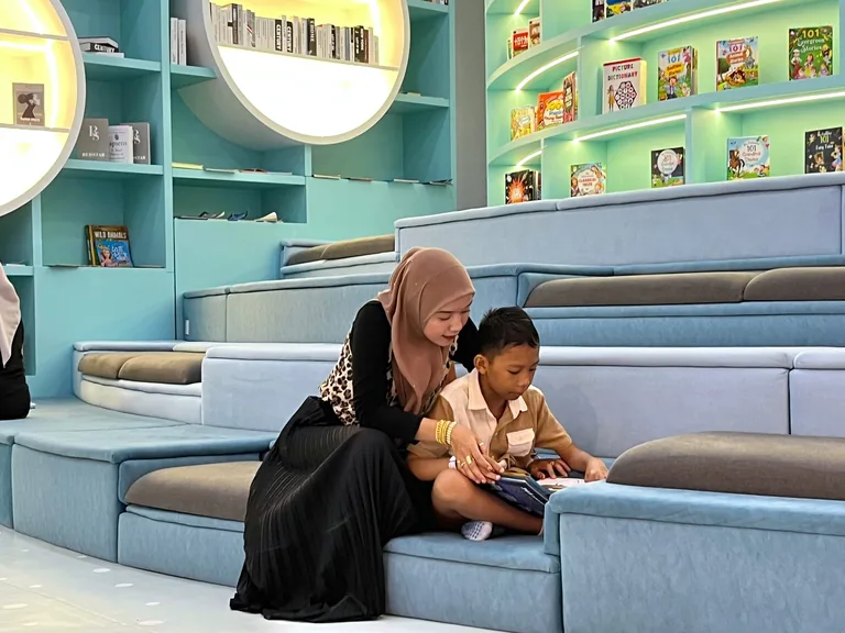 A parent reading with a child in UFOREA Penang's cozy reading area