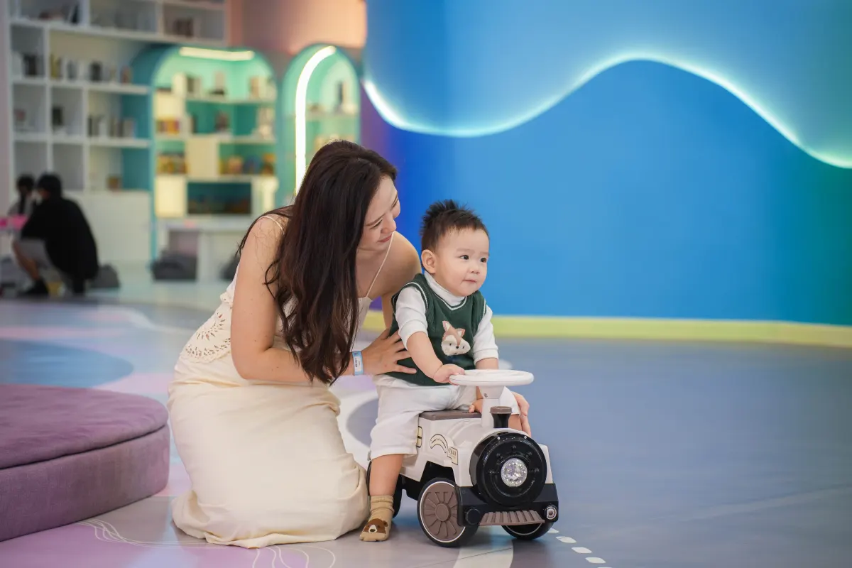 A mother steadying her toddler on a ride-on train in the toddler zone at UFOREA Penang
