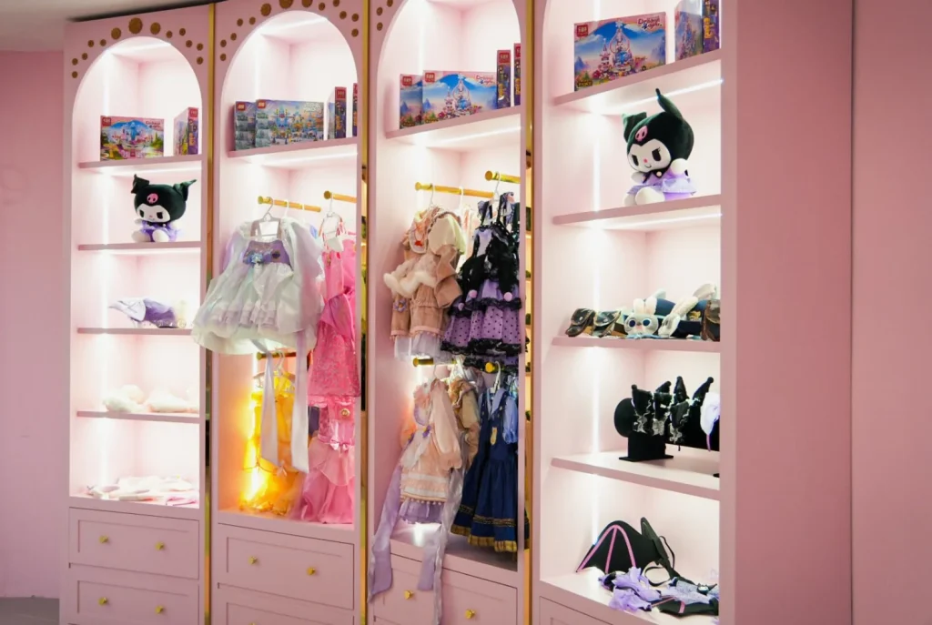 Backlit pink display shelves in the Makeover Castle at UFOREA Penang, filled with princess costumes, accessories, plush toys and dress-up outfits for children to choose from.